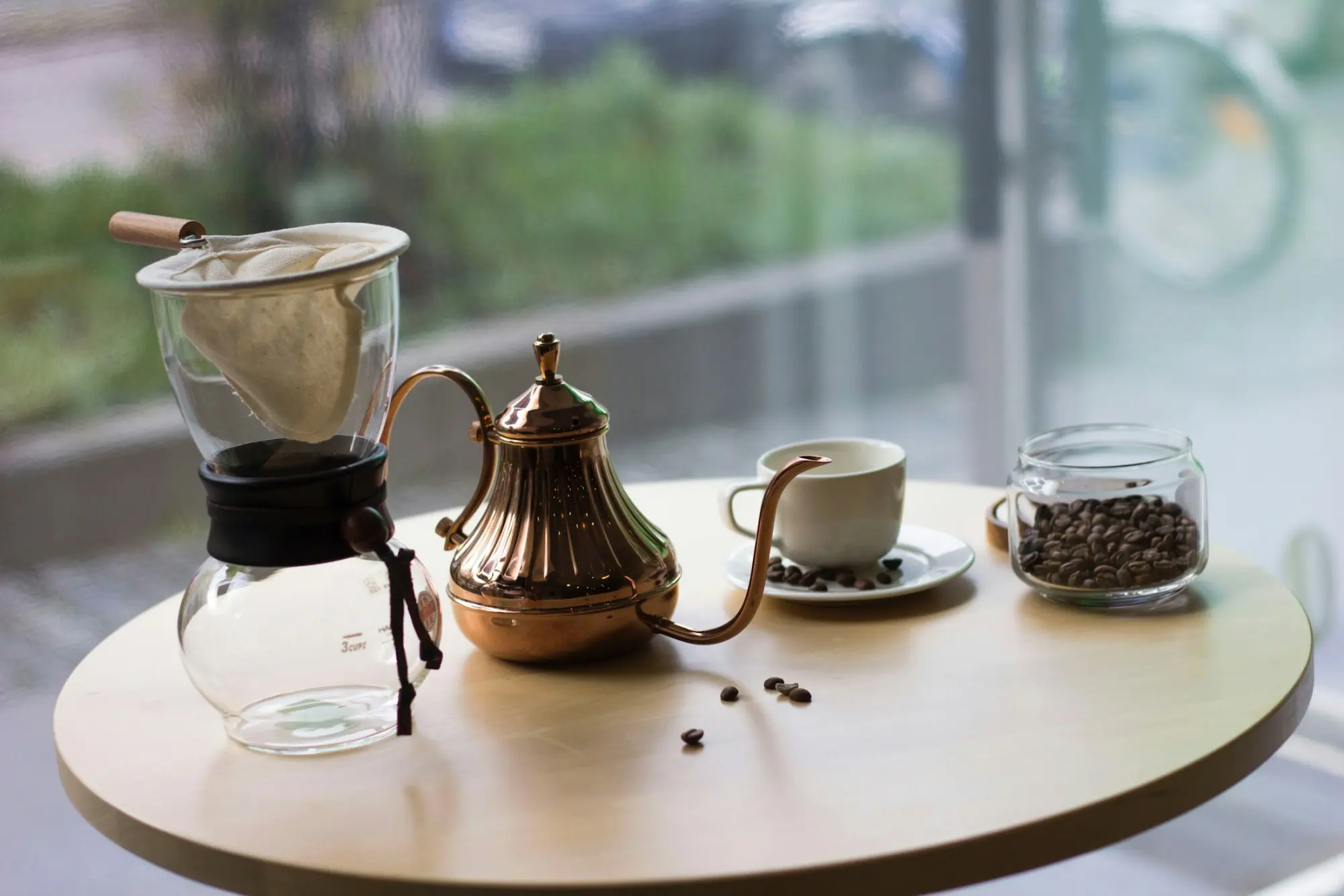 A pour-over brewer, copper kettle and cup on a café table