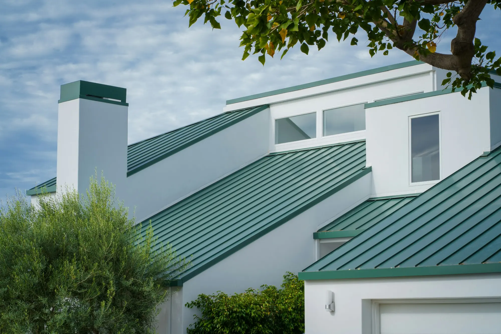 A white home with a green standing seam metal roof